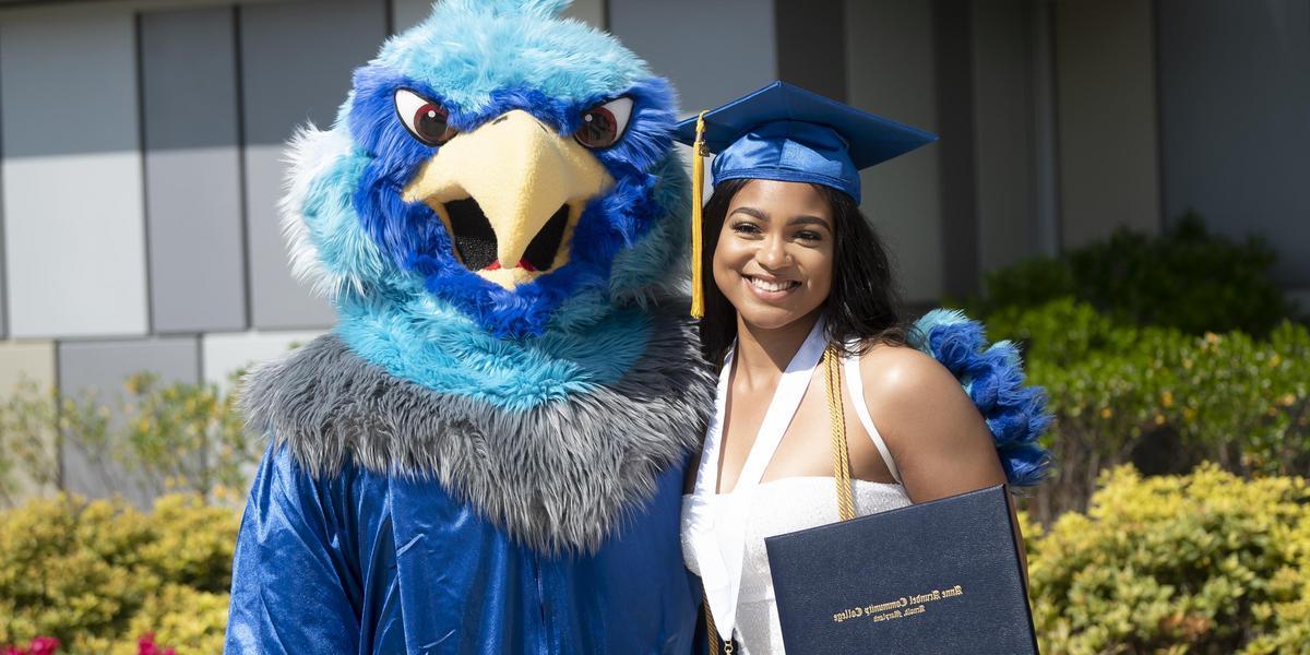 AACC grad posing with AACC mascot, Swoop